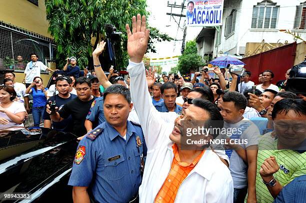 Philippine presidential candidate and former president Joseph Estrada waves to his supporters after casting his ballot at an elementary school in San...