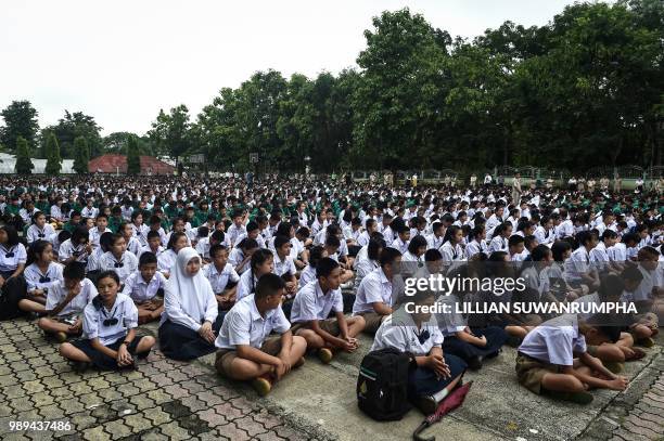 Thai school children with their teachers pray for their missing classmates from the grounds of Mae Sai Prasitsart school, near Tham Luang cave in...