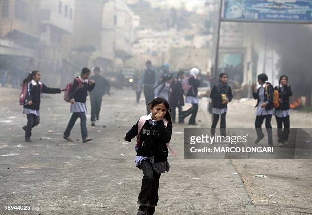 Palestinian schoolgirls run for cover during clashes in the West Bank town of Hebron on February 25, 2010. Around 100 Palestinians clashed with...