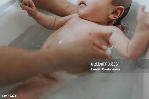 cropped hands bathing baby girl in bathtub at home - taking a bath stock pictures, royalty-free photos & images