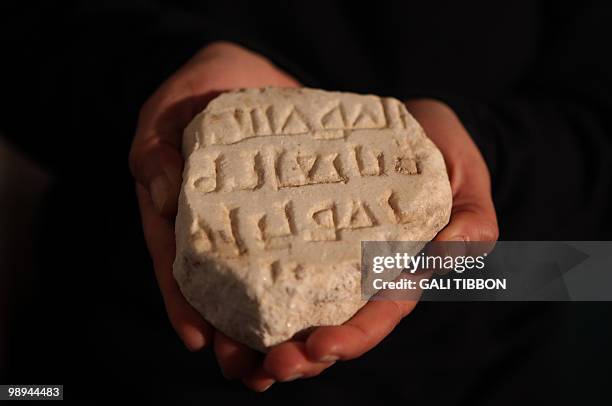 An Israeli archeologist holds on February 17, 2010 a fragment of a rare 1,100 year-old marble plaque bearing parts of an engraved Arabic inscription...