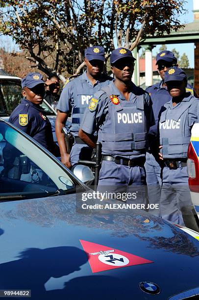 South African police stand guard as a car bearing the emblem of the Afrikaner Resistance Movement founded by Eugene Terre'Blanche is parked during...