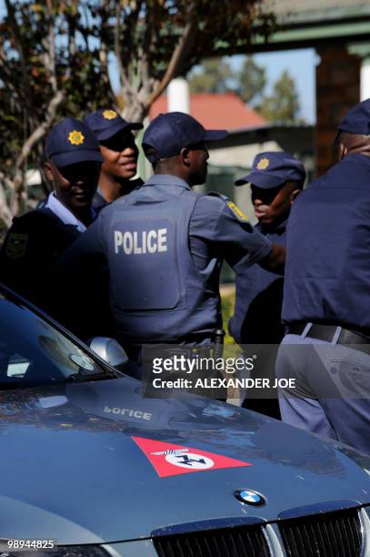 South African police stand guard as a car bearing the emblem of the Afrikaner Resistance Movement founded by Eugene Terre'Blanche is parked during...