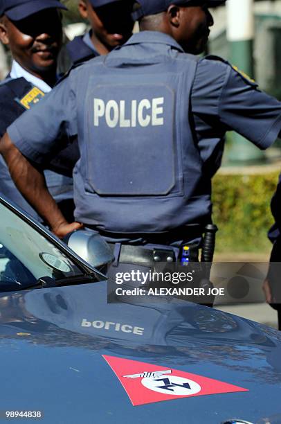 South African police stand guard as a car bearing the emblem of the Afrikaner Resistance Movement founded by Eugene Terre'Blanche is parked during...