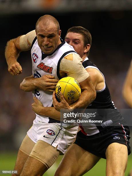 Chris Judd of the Blues handballs whilst being tackled by Steven Baker of the Saints during the round seven AFL match between the St Kilda Saints and...