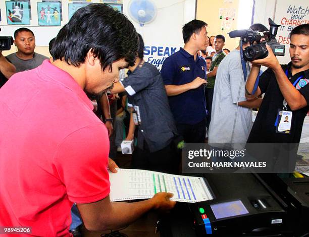 Philippine boxing hero Manny Pacquiao places his ballot paper into a vote counting machine as he casts his vote at a polling center in Kiamba,...