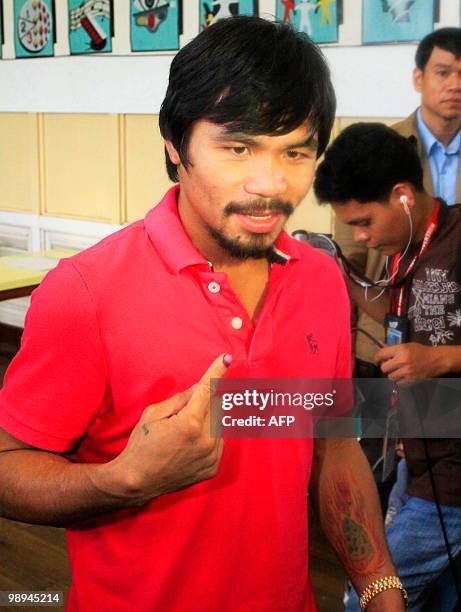 Philippine boxing hero Manny Pacquiao shows his finger marked with indelible ink after casting his vote at a polling center in Kiamba, Sarangani...