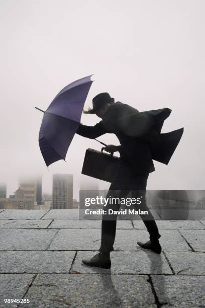 businessman with umbrella in the wind - umbrella wind stock pictures, royalty-free photos & images