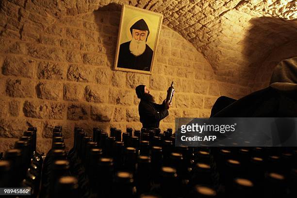 Maronite monk picks a bottle of organic wine at the reserve of the monastery of Mar Mussa in the mountains northeast of Beirut on January 14, 2010....