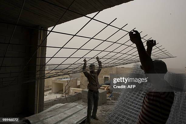 Palestinian laborers work on a construction site in the east Jerusalem settlement of Ramat Shlomo on May 10, 2010. The newly launched Middle East...