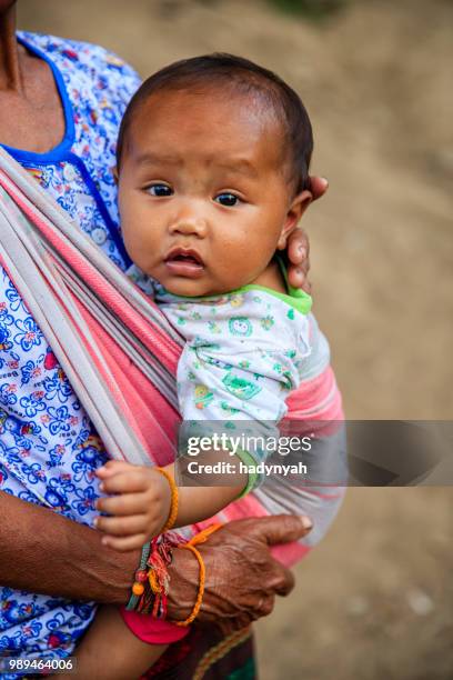 laotian grandmother sitting with a baby in a village in northern laos - laotian culture stock pictures, royalty-free photos & images