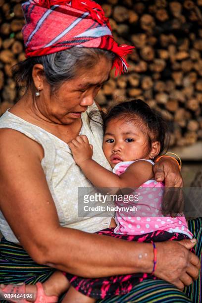 laotische großmutter sitzt mit kleinen mädchen in einem dorf im nördlichen laos - laotische kultur stock-fotos und bilder