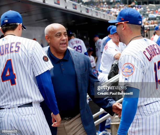 Former New York Mets Manager Omar Minaya walks through the dugout and talks with Asdrubal Cabrera and Wilmer Flores of the New York Mets before an...