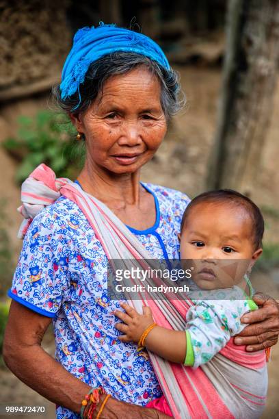 laotische großmutter sitzt mit einem baby in einem dorf im nördlichen laos - laotische kultur stock-fotos und bilder