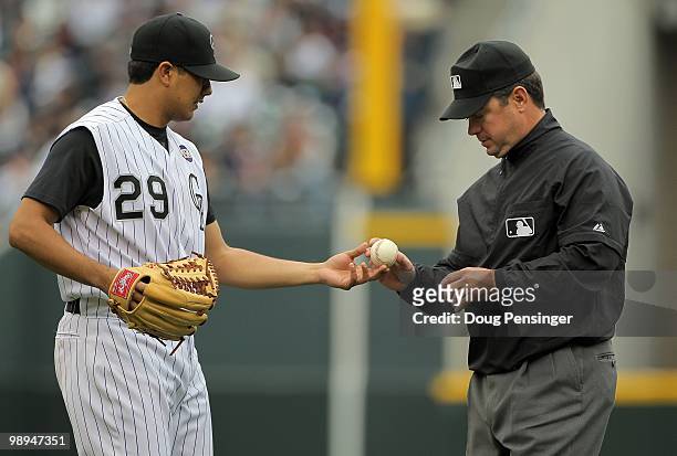 Umpire Rob Drake inspects the ball used by starting pitcher Jorge De La Rosa of the Colorado Rockies against the Florida Marlins at Coors Field on...