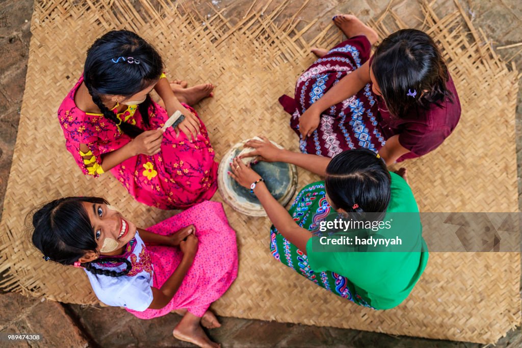Young Burmese girl putting thanaka paste on her friend's face, Bagan, Myanmar
