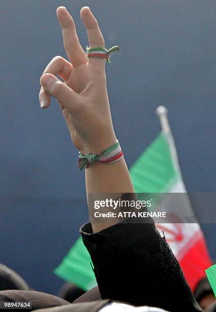 An Iranian woman flashes the V-sign of victory, with the colours of the national flag around her finger and wrist, during a mass rally held in Azadi...
