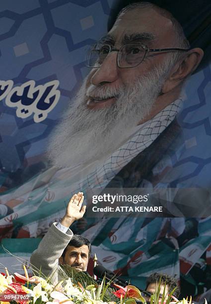 Iranian President Mahmoud Ahmadinejad waves as he stands in front of a huge portrait of Supreme leader Ayatollah Ali Khamenei before addressing tens...