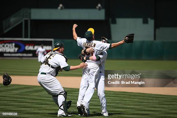 Dallas Braden of the Oakland Athletics celebrates his perfect game with teammates Landon Powell and Daric Barton after the game between the Tampa Bay...