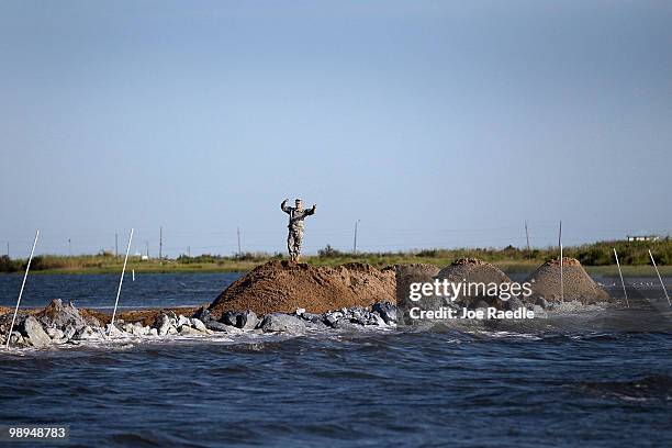 Louisiana National Guard Private Dallas Bacon guides a dump truck as they use dirt to create an earthen barrier as they try to protect an estuary...