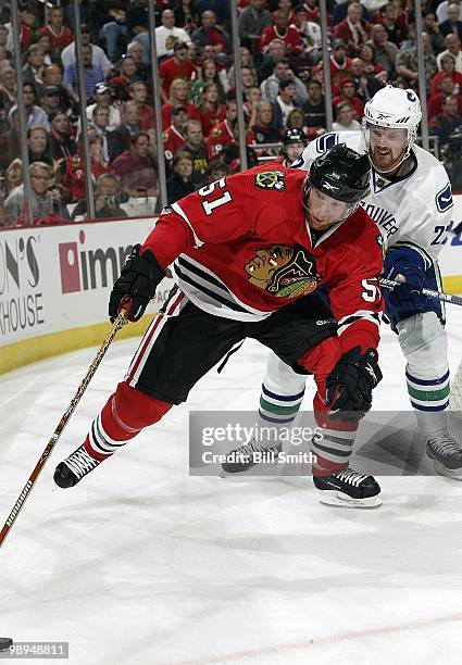 Brian Campbell of the Chicago Blackhawks reaches for the puck as Daniel Sedin of the Vancouver Canucks watches from behind at Game Two of the Western...