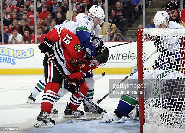 Jonathan Toews of the Chicago Blackhawks tries to push the puck into the net as Christian Ehrhoff of the Vancouver Canucks pushes from behind at Game...