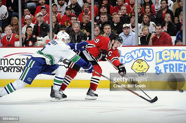 Jonathan Toews of the Chicago Blackhawks shoots the puck as Christian Ehrhoff of the Vancouver Canucks reaches from behind at Game Two of the Western...