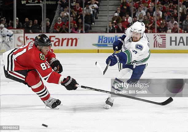 Daniel Sedin of the Vancouver Canucks shoots the puck as Marian Hossa the Chicago Blackhawks reaches across at Game Two of the Western Conference...