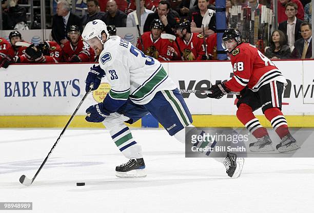 Henrik Sedin of the Vancouver Canucks approaches the puck as Patrick Kane of the Chicago Blackhawks watches from the side at Game Two of the Western...