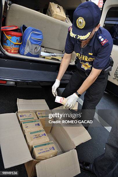 Police investigator inspects boxes containing envelopes with cash from an abandoned vehicle from the convoy of congressional candidate Del Abaya in...