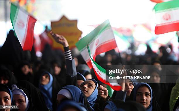 Schoolgirls wave Iranian flags as they mark the start of 10 days of celebrations for the anniversary of the Islamic revolution at the Behesht-e Zahra...