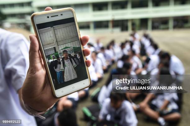 Thai student shows a picture of missing classmate Prachak Sutham, before a prayer ceremony at Mae Sai Prasitsart school, near Tham Luang cave in Khun...