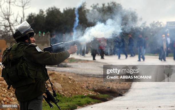 An Israeli soldier fires tear gas to disperse Palestinian protesters on February 5, 2010 during a weekly demonstration against Israeli settlement...