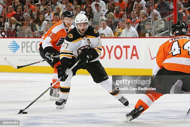 Patrice Bergeron of the Boston Bruins skates with the puck in on Kimmo Timonen and Claude Giroux of the Philadelphia Flyers in Game Four of the...