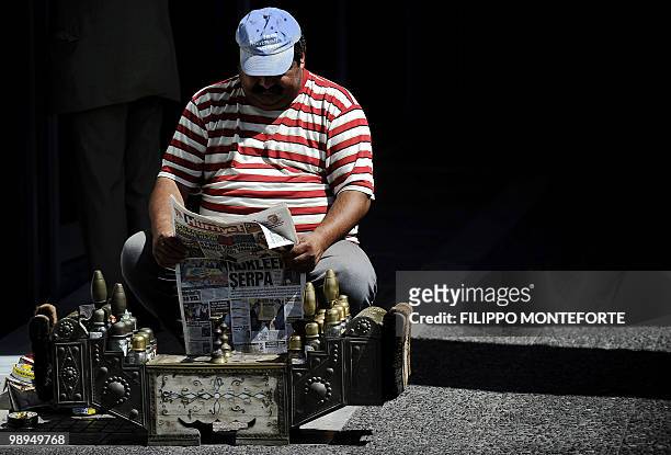 Shoe shiner reads a newspaper in downtown Athens on May 10, 2010. European nations and the IMF on May 10, 2010 set up a one-trillion-dollar war chest...