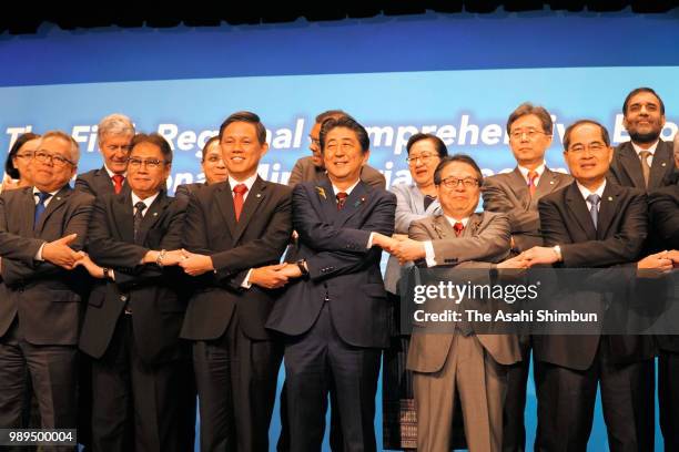 Japanese Prime Minister Shinzo Abe and ministers shake hands during a family photo session of the Regional Comprehensive Economic Partnership on July...