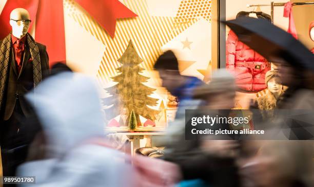 Pedestrians hurry past festively decorated shop windows at the Zeil shopping mile in Frankfurt am Main, Germany, 22 December 2017. Photo: Frank...