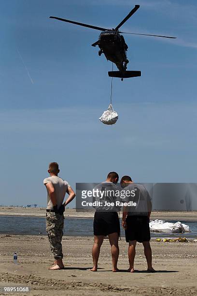 Louisiana National Guard helicopter airlifts sling load sand bags into place as they create a barrier in an attempt to protect an estuary from the...