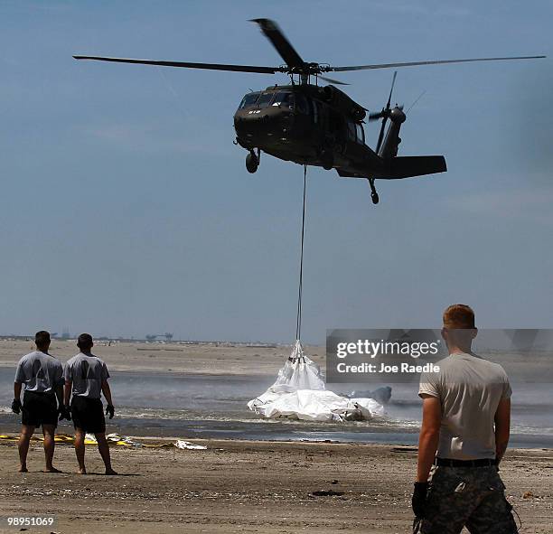 Louisiana National Guard helicopter airlifts sling load sand bags into place as they create a barrier in an attempt to protect an estuary from the...