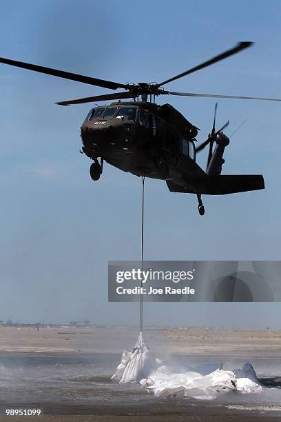 Louisiana National Guard helicopter airlifts sling load sand bags into place as they create a barrier in an attempt to protect an estuary from the...