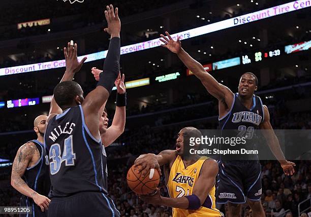 Kobe Bryant of the Los Angeles Lakers looks to pass the ball as he is covered bby C.J. Miles, Carlos Boozer and Wesley Matthews of the Utah Jazz...