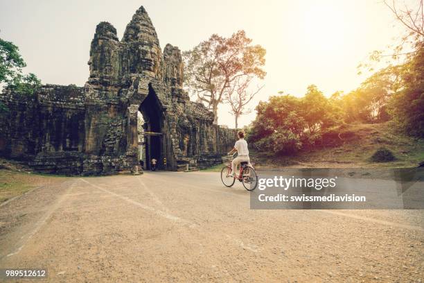 mujer joven en bicicleta en templo complejo en camboya - cambodia fotografías e imágenes de stock