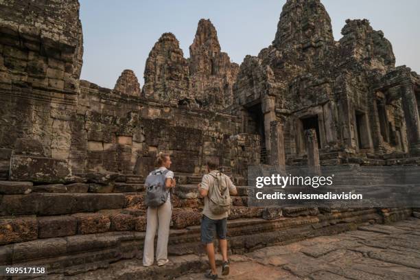 aantal toeristische reizen asia en prachtige oude tempels en ruïnes van de oude overweegt bij zonsondergang; mensen ontdekking exploratie concept - bayontempel stockfoto's en -beelden