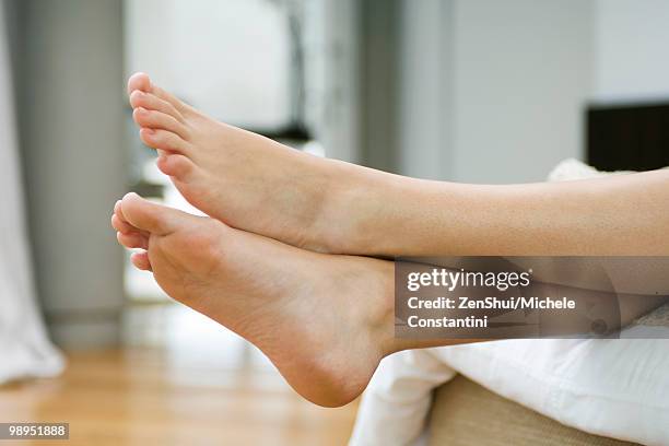 woman's bare feet, legs crossed at ankle - womans bare feet fotografías e imágenes de stock