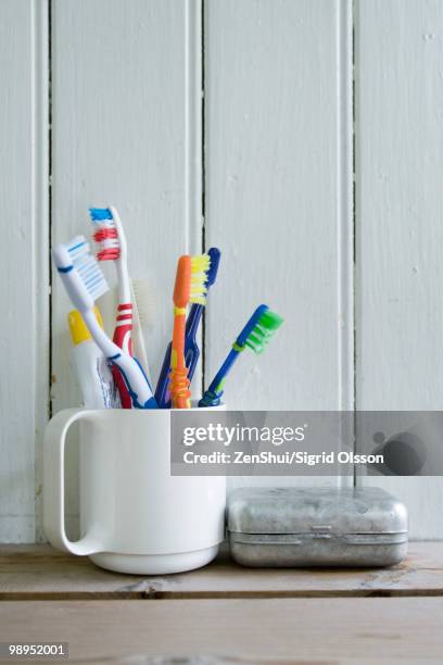 toothbrushes in mug on shelf - toothbrush stock pictures, royalty-free photos & images