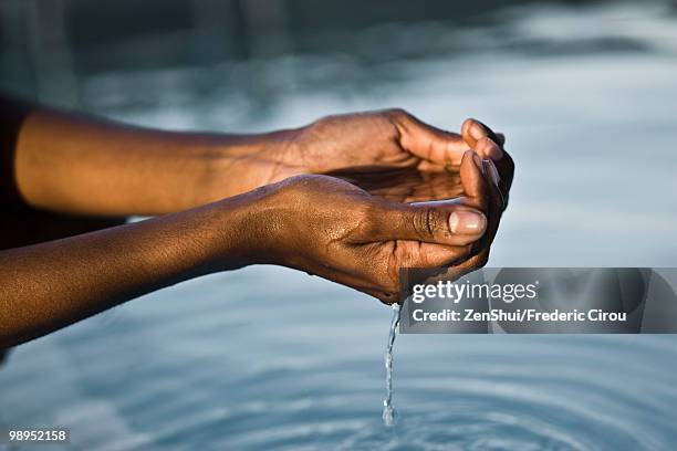 water flowing from cupped hands - hohle hände stock-fotos und bilder