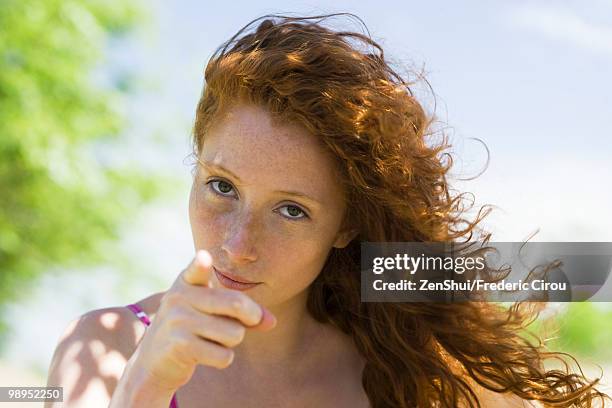 young woman with look of reproach pointing finger at camera - biasimo foto e immagini stock