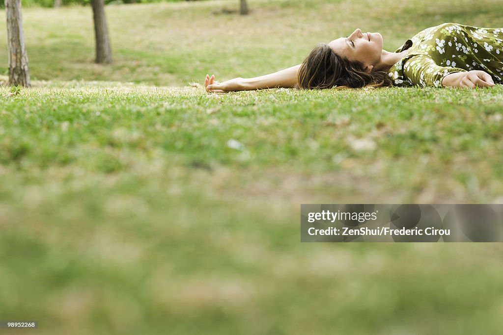 Woman lying on grass, daydreaming