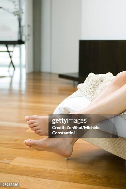 woman's bare feet and legs dangling off end of bed - womans bare feet fotografías e imágenes de stock