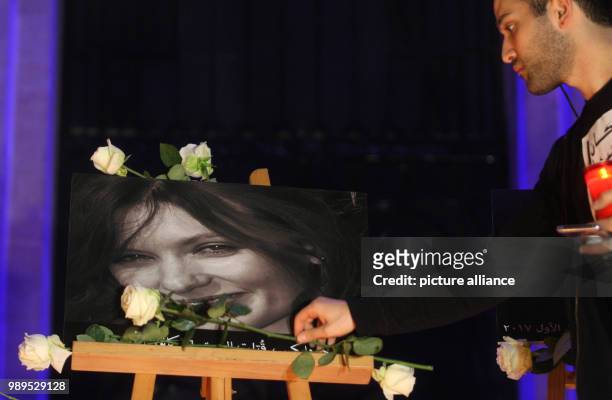 Lebanese activist lays a flower at the poster of murdered British diplomat Rebecca Dykes during a candlelight vigil to condemn violence against...